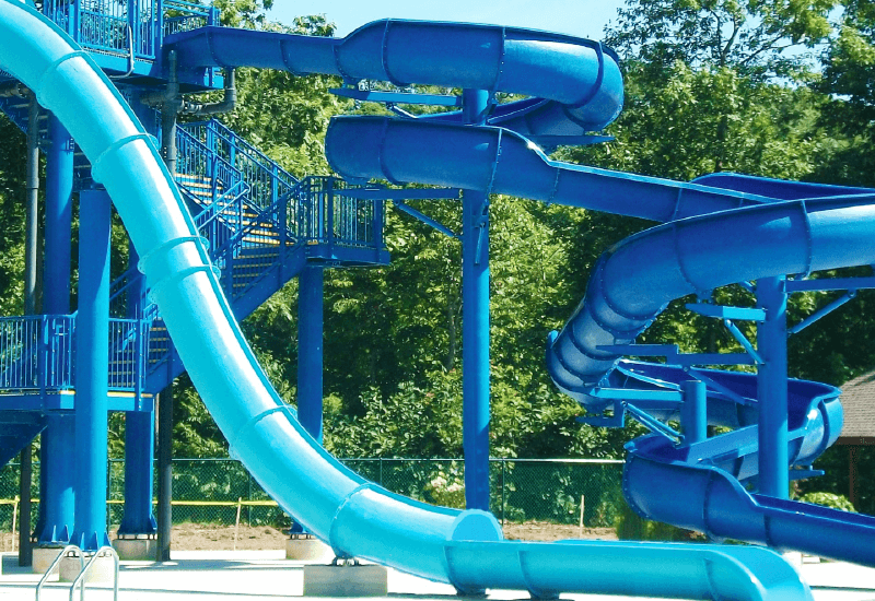 Toboggans aquatiques bleus en plein air : pistes tubulaires, tours et escaliers métalliques d'accès